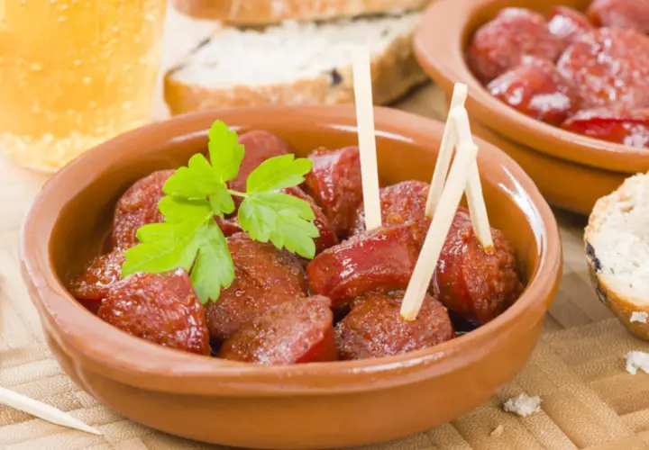 Delicioso chorizo a la sidra en cazuela de barro, adornado con perejil fresco. Acompañado de pan y una cerveza.