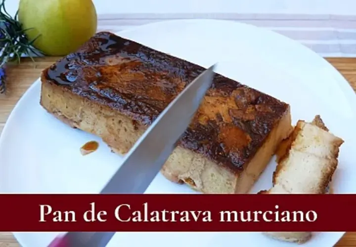 Un cuchillo corta un trozo de pan de Calatrava murciano, un postre dulce y dorado, servido en un plato blanco.