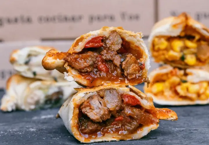 Empanada de carne jugosa y sabrosa, cortada por la mitad, revelando su relleno de carne y pimientos.