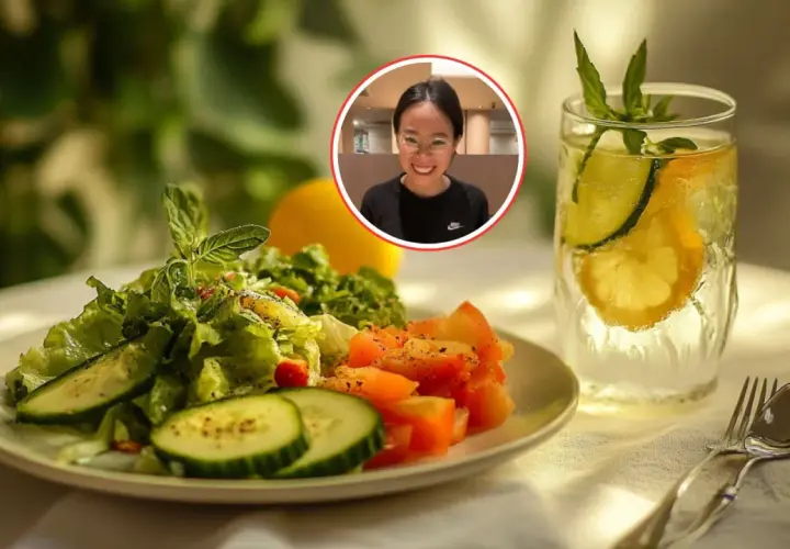 Una mujer sonríe mientras disfruta de una refrescante ensalada de pepino y una bebida con limón y pepino.