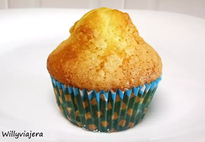 Una magdalena casera, dorada y esponjosa, en su envoltorio de papel con motivos verdes y azules. ¡Perfecta para el desayuno!