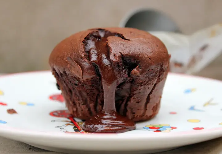 Coulant de chocolate tibio con centro líquido, servido en un plato blanco con dibujos de colores.