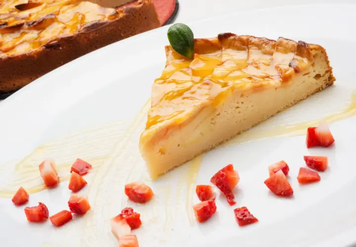 Una rebanada de tarta de manzana tradicional, glaseada y decorada con fresas picadas y una hoja verde.