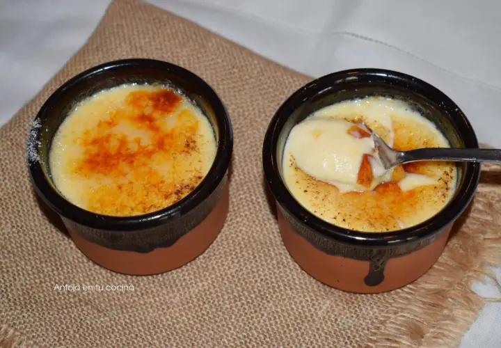 Dos deliciosas cremas catalanas, una con una cucharada lista para disfrutar, sobre una tela rústica.