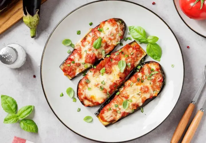 Berenjenas asadas con tomate y queso, un plato delicioso de recetas con berenjenas. Decoradas con albahaca fresca.