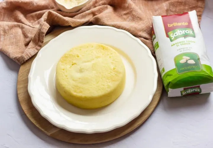 Pastel de arroz dorado y esponjoso en plato blanco, junto a un paquete de arroz Sabroz.