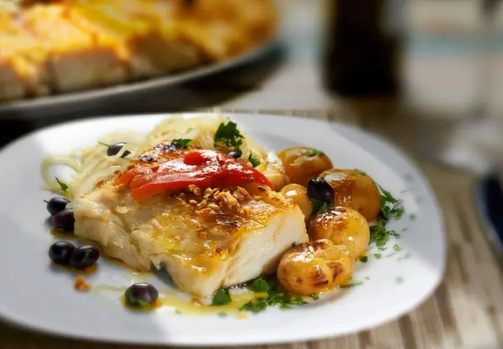 Filete de bacalao skrei asado con patatas, aceitunas y pimientos rojos.