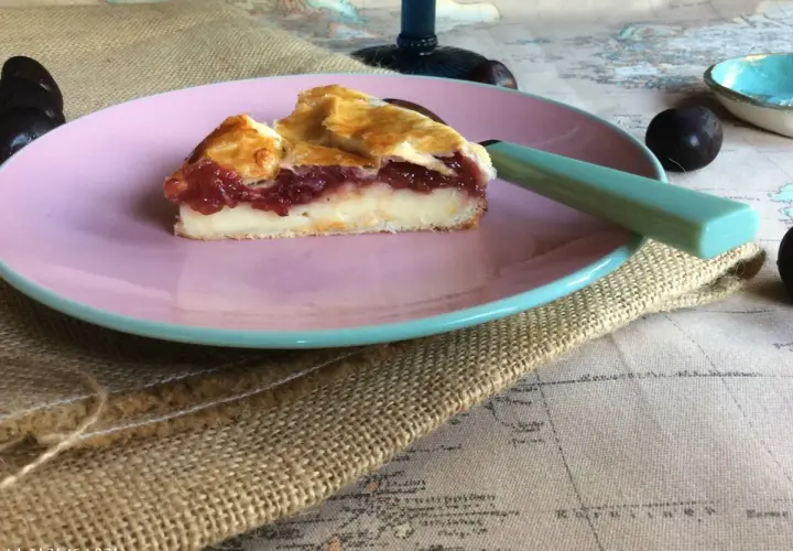 Porción de pastel vasco con relleno de crema y frutos rojos, servida en plato rosa.