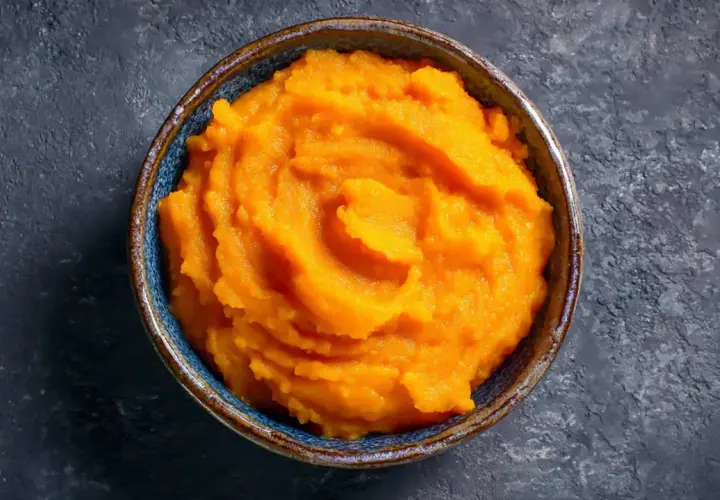 Un cuenco de cremoso puré de boniato, con su vibrante color naranja, listo para ser disfrutado.