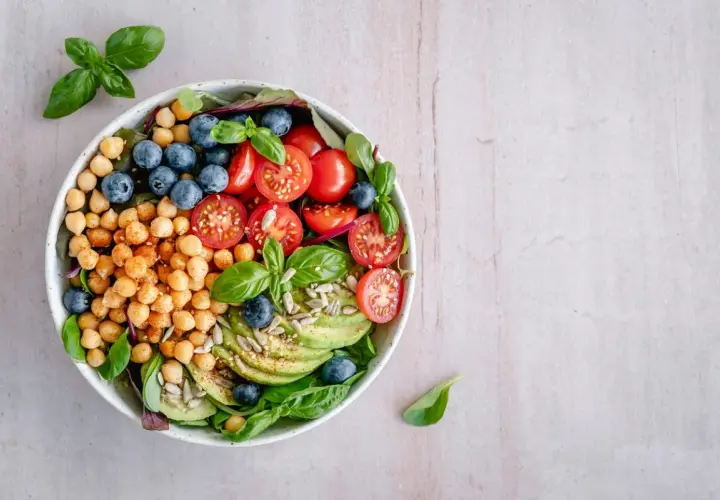 Deliciosa ensalada de legumbres con garbanzos, arándanos, tomates cherry, aguacate y semillas.