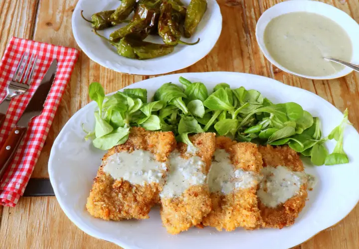 Escalopines al cabrales crujientes, servidos con ensalada verde y pimientos de Padrón.