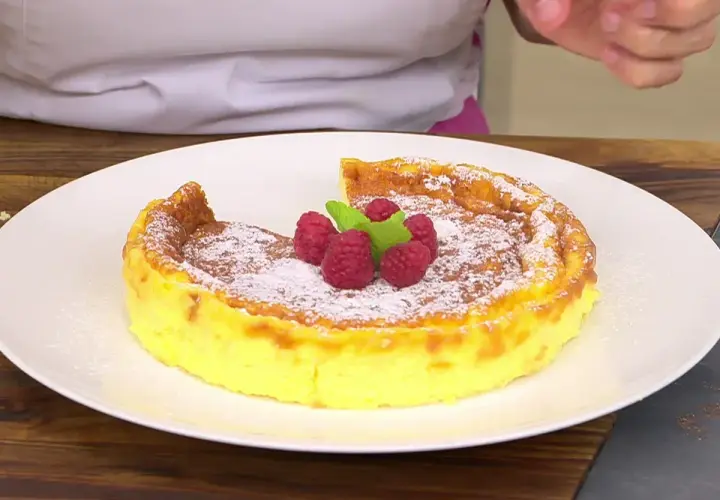 Tarta de queso Eva Arguiñano, dorada y espolvoreada con azúcar glas, coronada con frambuesas y menta. ¡Un postre irresistible!