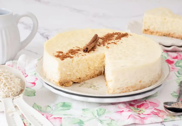 Deliciosa tarta de arroz cremosa, decorada con canela en rama y espolvoreada. Un trozo ya servido.