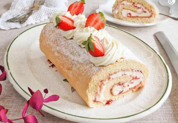 Un delicioso brazo de gitano con crema y fresas, espolvoreado con azúcar glas.
