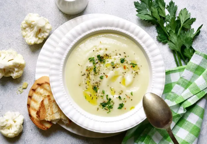 Crema de coliflor, una de las mejores coliflor recetas, servida con pan tostado y perejil fresco.