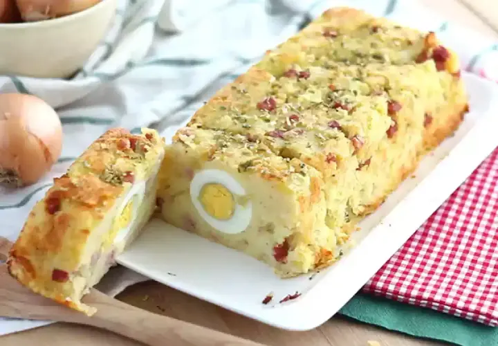 Un delicioso pastel de patata con trozos de bacon y huevos duros en su interior, espolvoreado con hierbas.