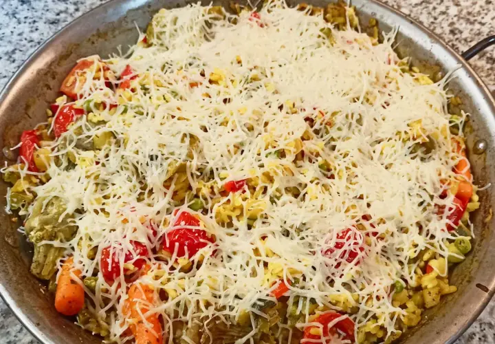 Arroz a la milanesa listo para hornear, con verduras y abundante queso rallado.
