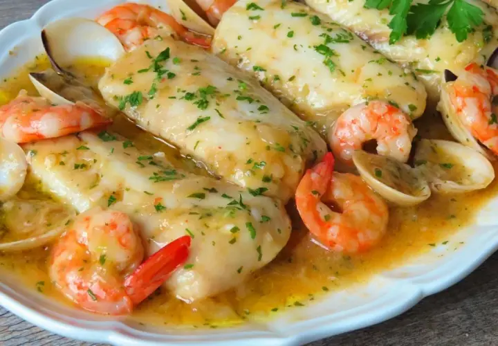 Merluza a la marinera con gambas y almejas, un plato delicioso bañado en salsa.