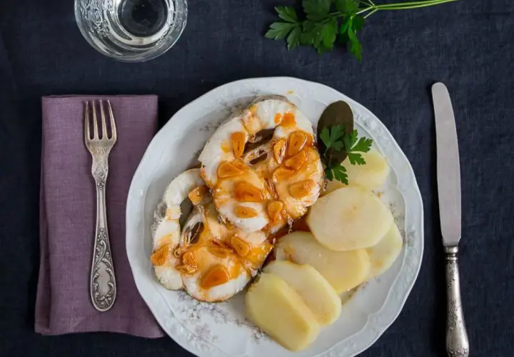 Merluza a la gallega con patatas cocidas, ajo dorado y perejil. Un plato tradicional listo para disfrutar.