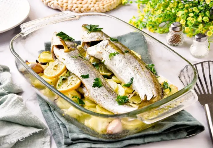 Pescadilla al horno con patatas, limón y ajo, recién salida del horno.