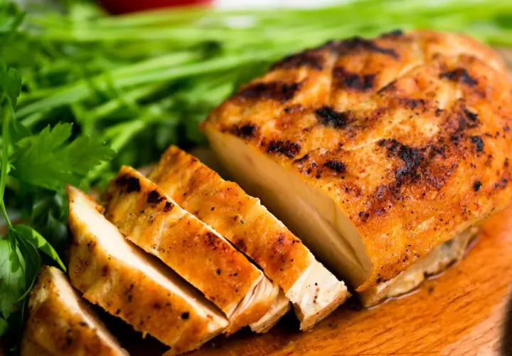 Pechuga de pollo a la parrilla, jugosa y dorada, lista para ser parte de tus recetas con pechuga de pollo. Acompañada de perejil fresco.