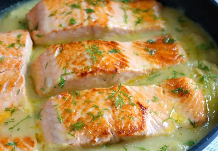 Filetes de salmón dorados en una cremosa salsa de eneldo, perfectos para tus recetas con salmón.
