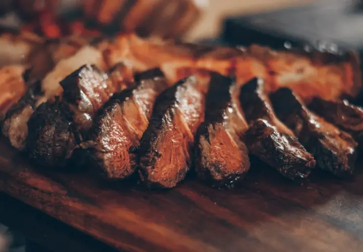 Filete de ternera jugoso y perfectamente cocinado, cortado en rodajas y servido en una tabla de madera.
