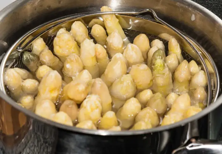 Espárragos blancos cocinándose en una olla.