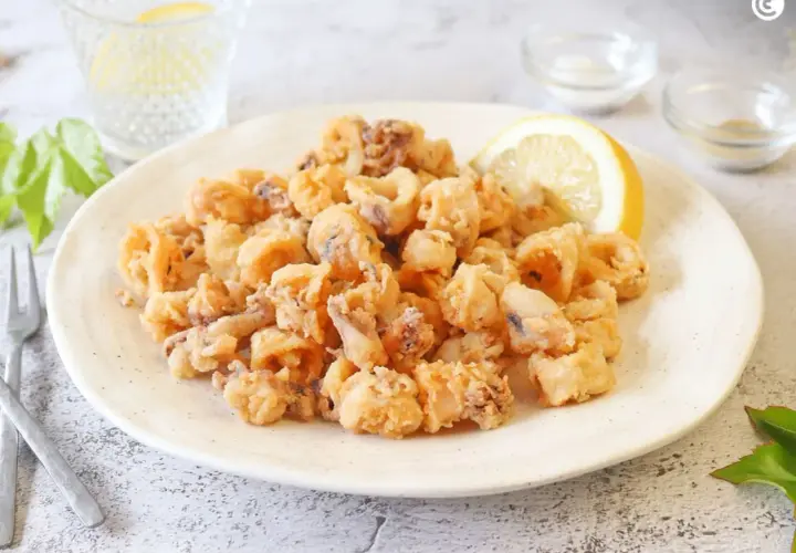 Un plato generoso de chipirones fritos crujientes, adornado con una rodaja de limón.