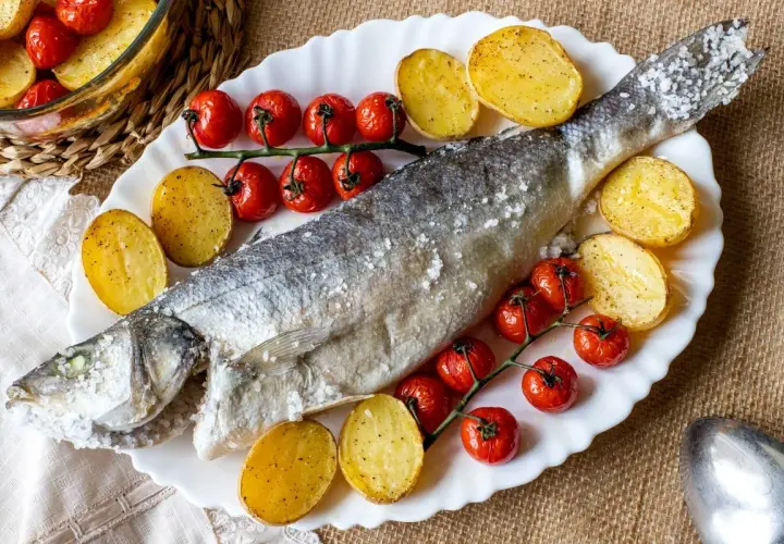 Lubina a la sal entera, horneada con patatas y tomates cherry. Un plato principal delicioso y saludable.