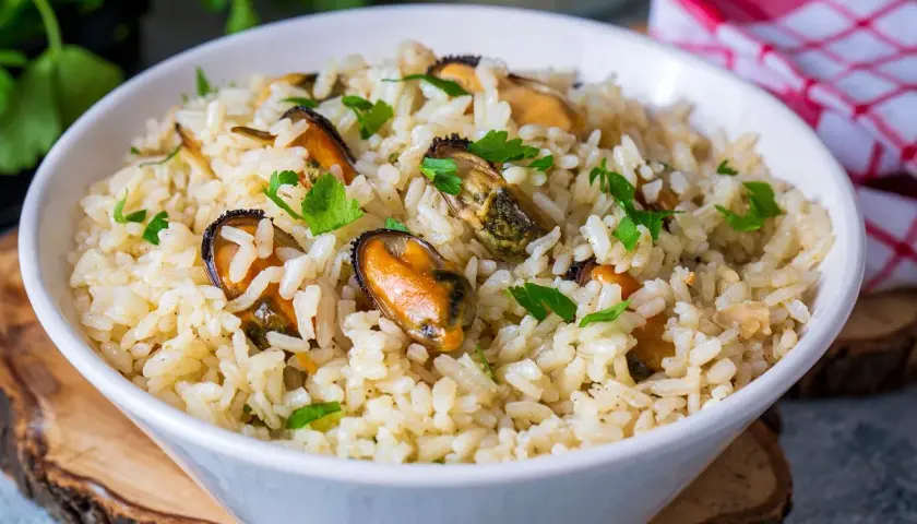 Un tazón de arroz con mejillones y perejil picado. Un plato delicioso y fácil de preparar.