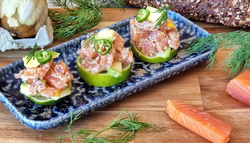 Tartar de salmón fresco servido en mitades de lima, adornado con aguacate y jalapeño.