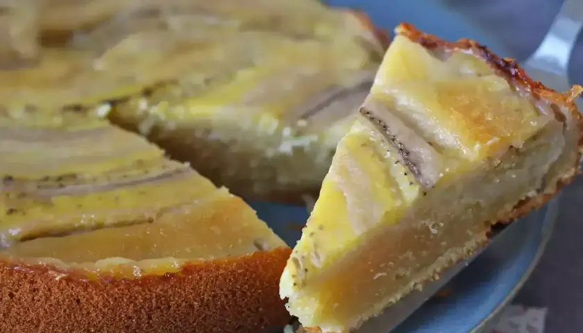 Un delicioso bizcocho de plátano, con una rebanada servida en un plato azul.