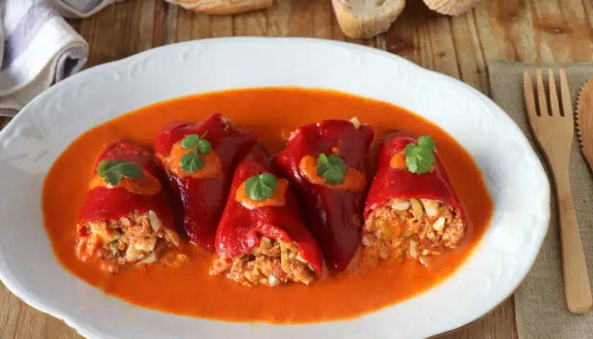 Pimientos del piquillo rellenos de atún y huevo, servidos en una salsa roja cremosa.