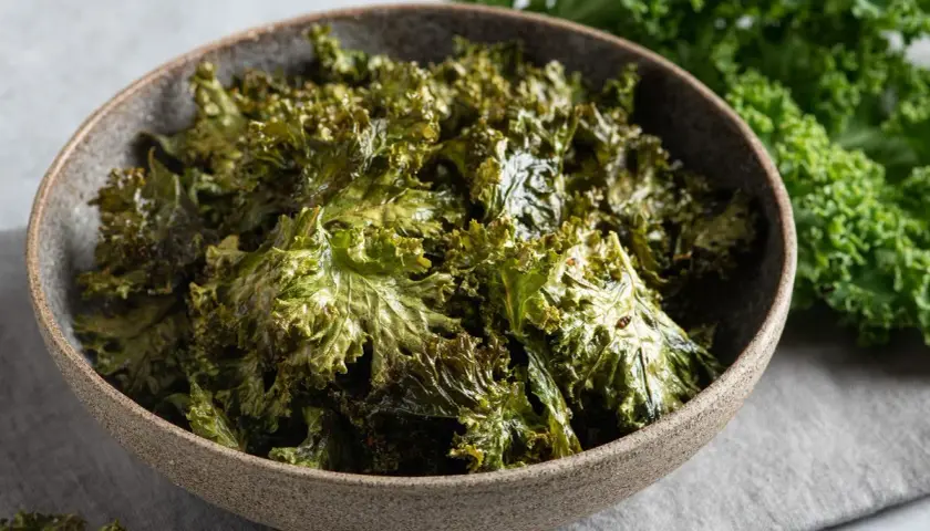 Crujientes chips de kale horneados en un tazón, perfectos para tus recetas con kale.