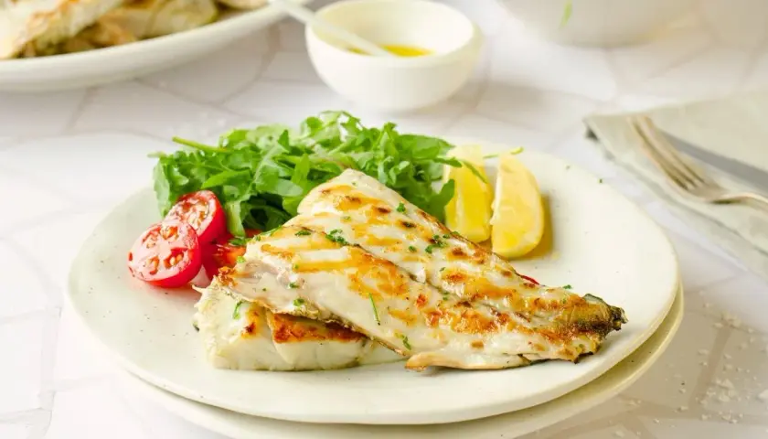 Deliciosa corvina a la plancha, servida con rúcula fresca, tomates cherry y gajos de limón. Un plato ligero y sabroso.