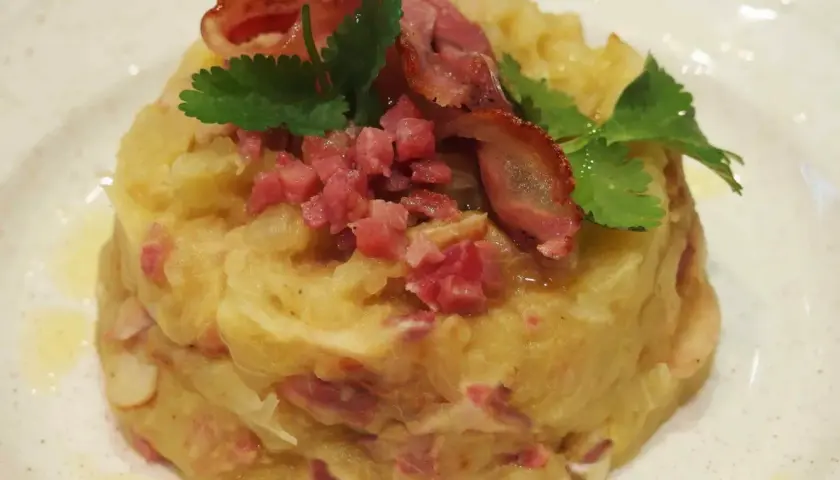 Trinxat de la Cerdanya, un plato tradicional con patata, col y trocitos de tocino, coronado con bacon crujiente y perejil.