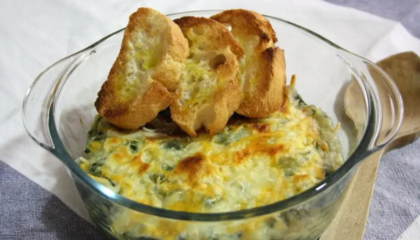 Delicioso plato de espinacas con bechamel gratinado, coronado con tostaditas de pan.
