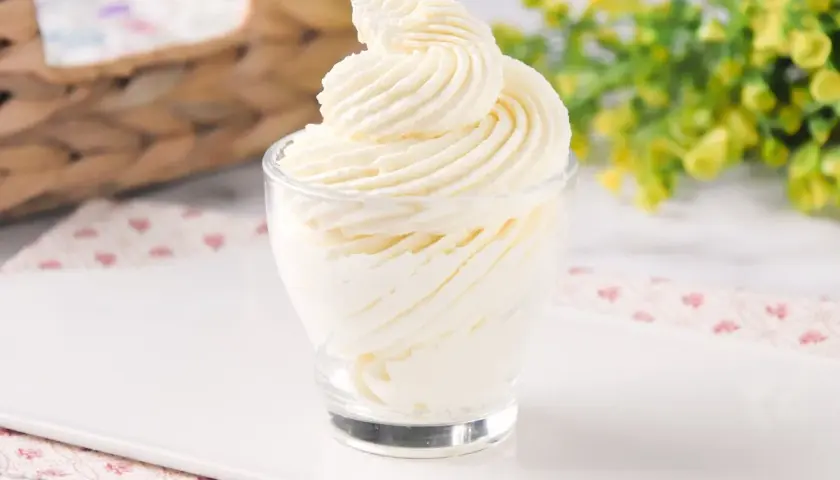 Delicioso frosting de queso cremoso, decorado en espiral, servido en un vaso de vidrio.