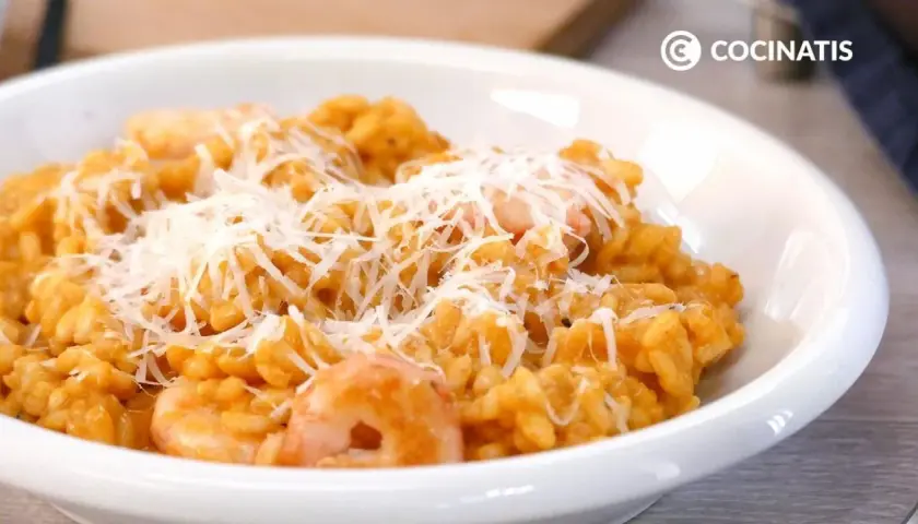 Un cremoso risotto de gambas, cubierto con queso rallado, listo para disfrutar.