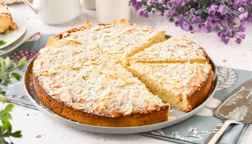 Tarta de almendras, espolvoreada con azúcar glas y almendras laminadas, lista para ser servida.