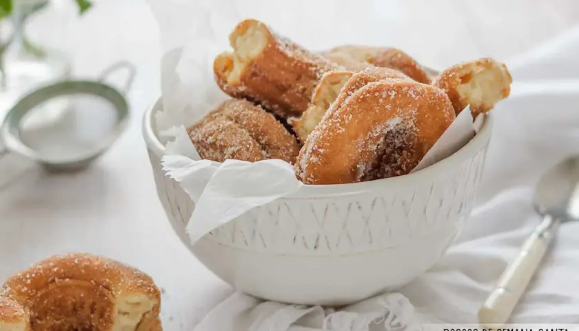 Roscos de Semana Santa espolvoreados con azúcar, servidos en un cuenco blanco.