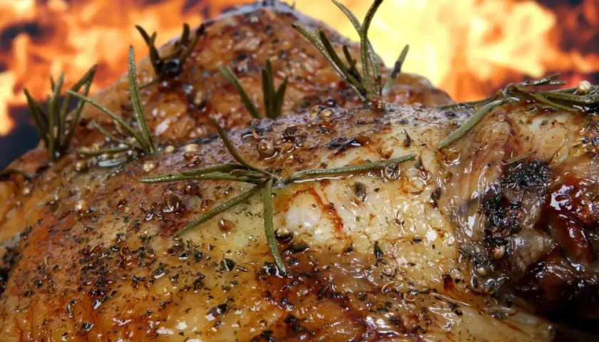 Pierna de cordero al horno, dorada y jugosa, con romero fresco y especias, lista para ser disfrutada.