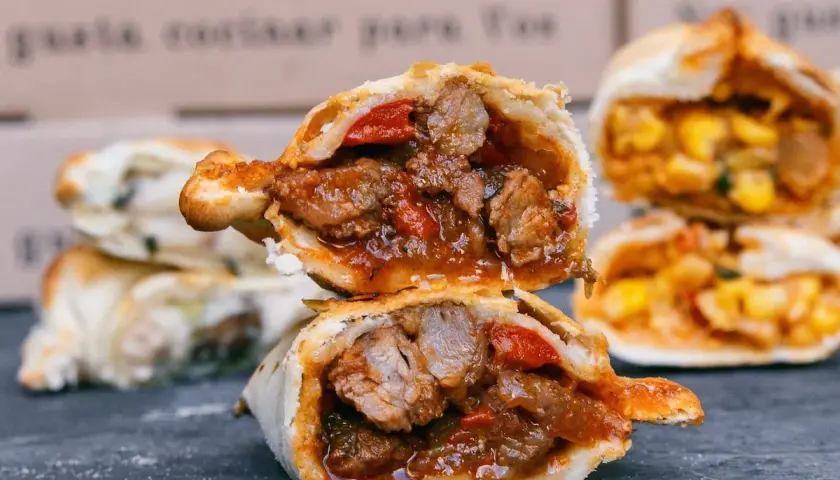 Empanada de carne jugosa y sabrosa, cortada por la mitad, revelando su relleno de carne y pimientos.
