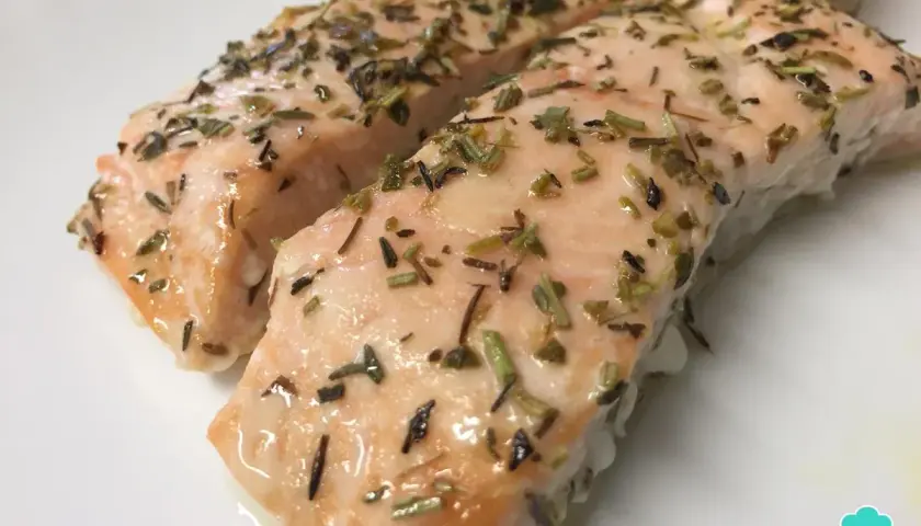 Dos jugosos filetes de salmón al horno, cubiertos con hierbas aromáticas y un toque de limón.