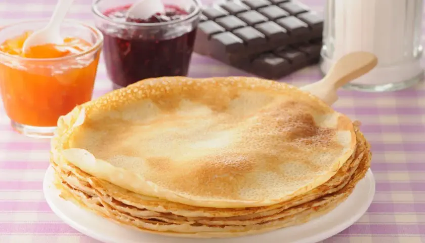 Una pila de crepes doradas, listas para disfrutar con mermelada de frutos rojos, albaricoque y chocolate. ¡Una deliciosa receta crepes!