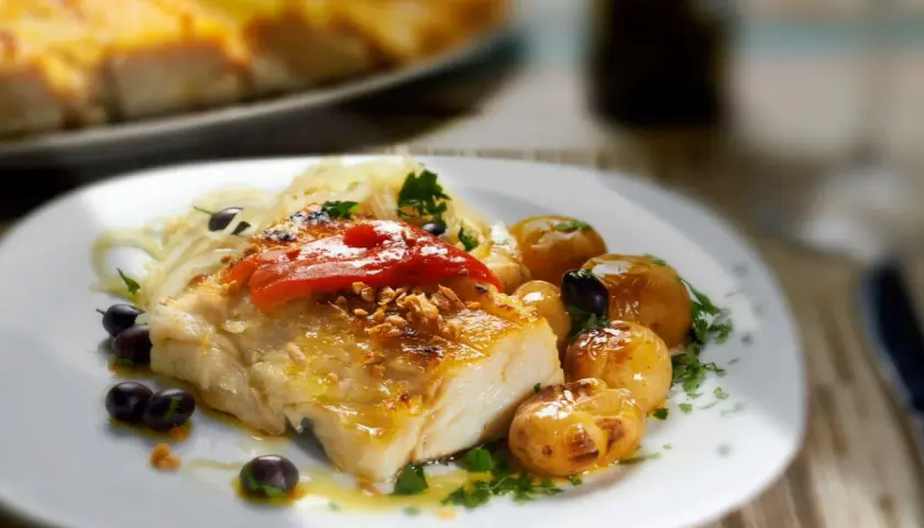 Filete de bacalao skrei asado con patatas, aceitunas y pimientos rojos.