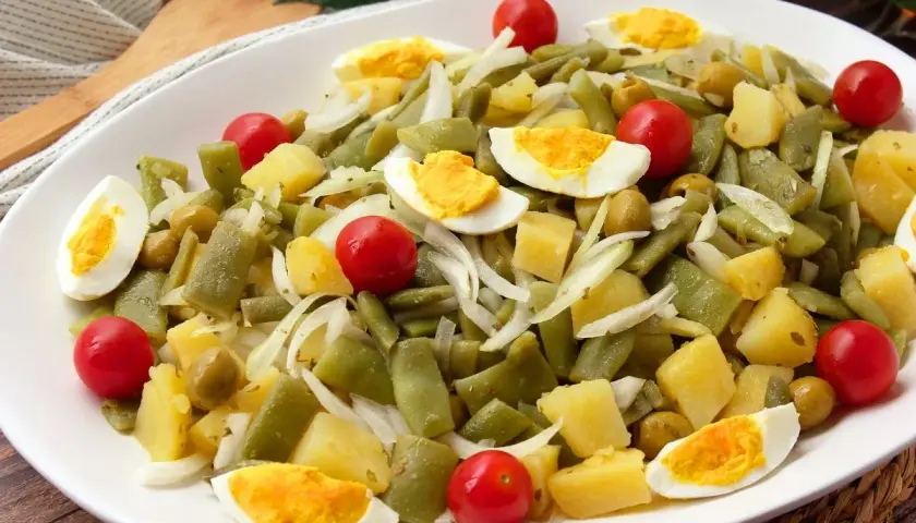 Deliciosa ensalada de judías verdes con patatas, huevo duro, tomates cherry y aceitunas. Un plato fresco y nutritivo.