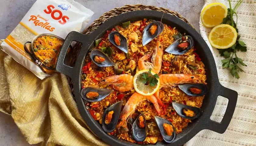 Paella mixta con gambas, mejillones y arroz dorado, lista para disfrutar.