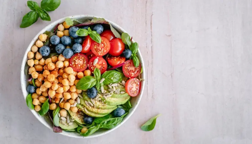 Deliciosa ensalada de legumbres con garbanzos, arándanos, tomates cherry, aguacate y semillas.
